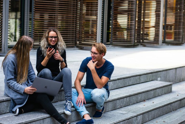 Three Persons Sitting on the Stairs Talking With Each Other